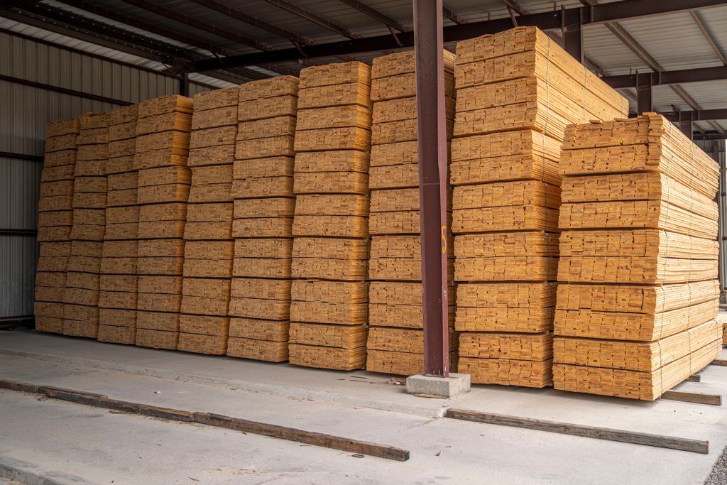 Large stacks of neatly arranged wood planks in an industrial storage facility.